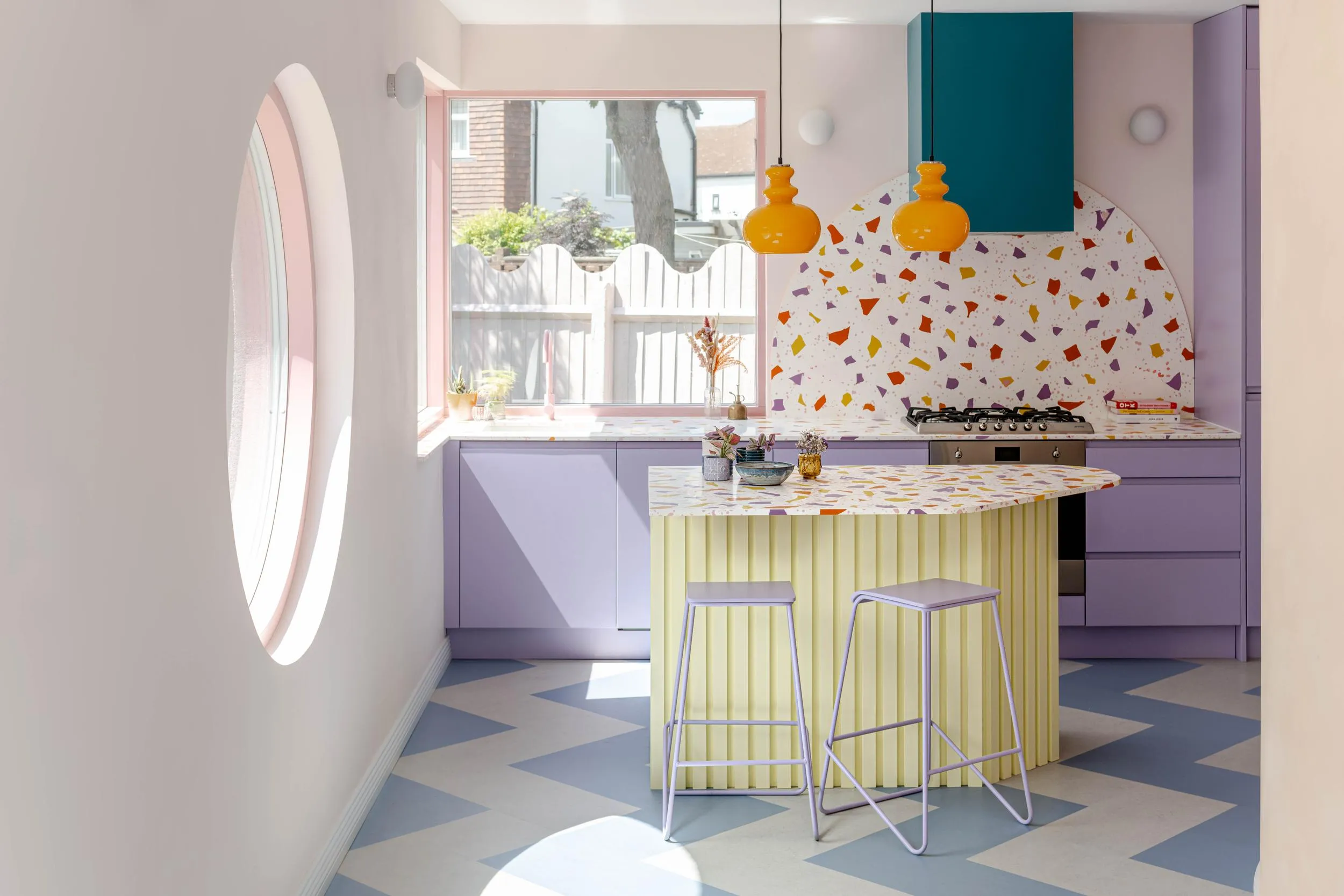 Photo of the kitchen space, showing the kitchen island and colourful accents on the floor and the wall. By Office S&M, RIBA Chartered Architectural Practice in London.