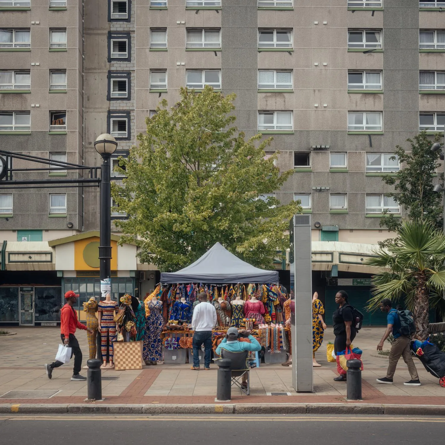 Photo of the existing building outside, with a market stool and people around. By Office S&M, RIBA Chartered Architectural Practice in London.