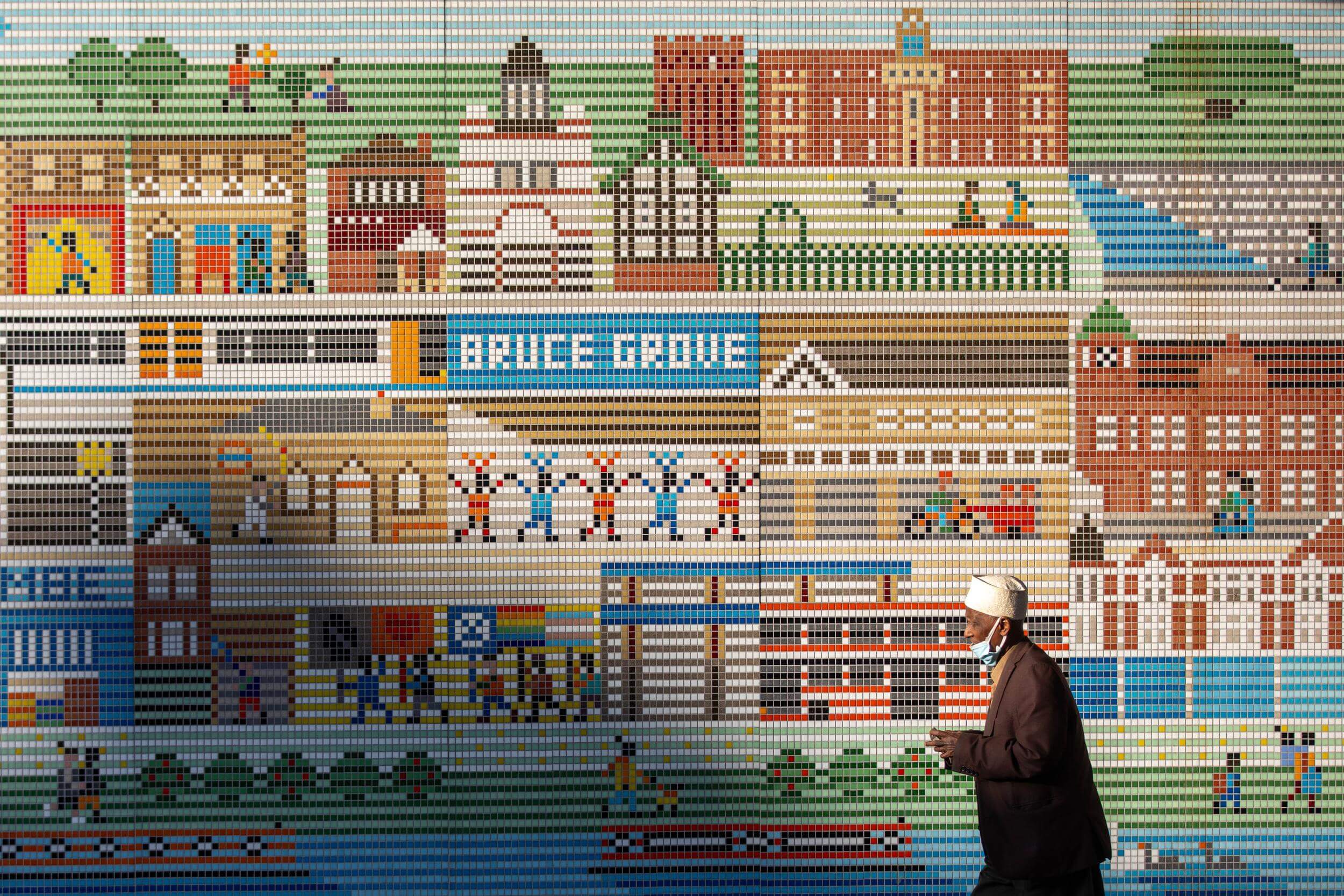 Main mosaic mural with a person walking in front of it. By Office S&M, RIBA Chartered Architectural Practice in London.