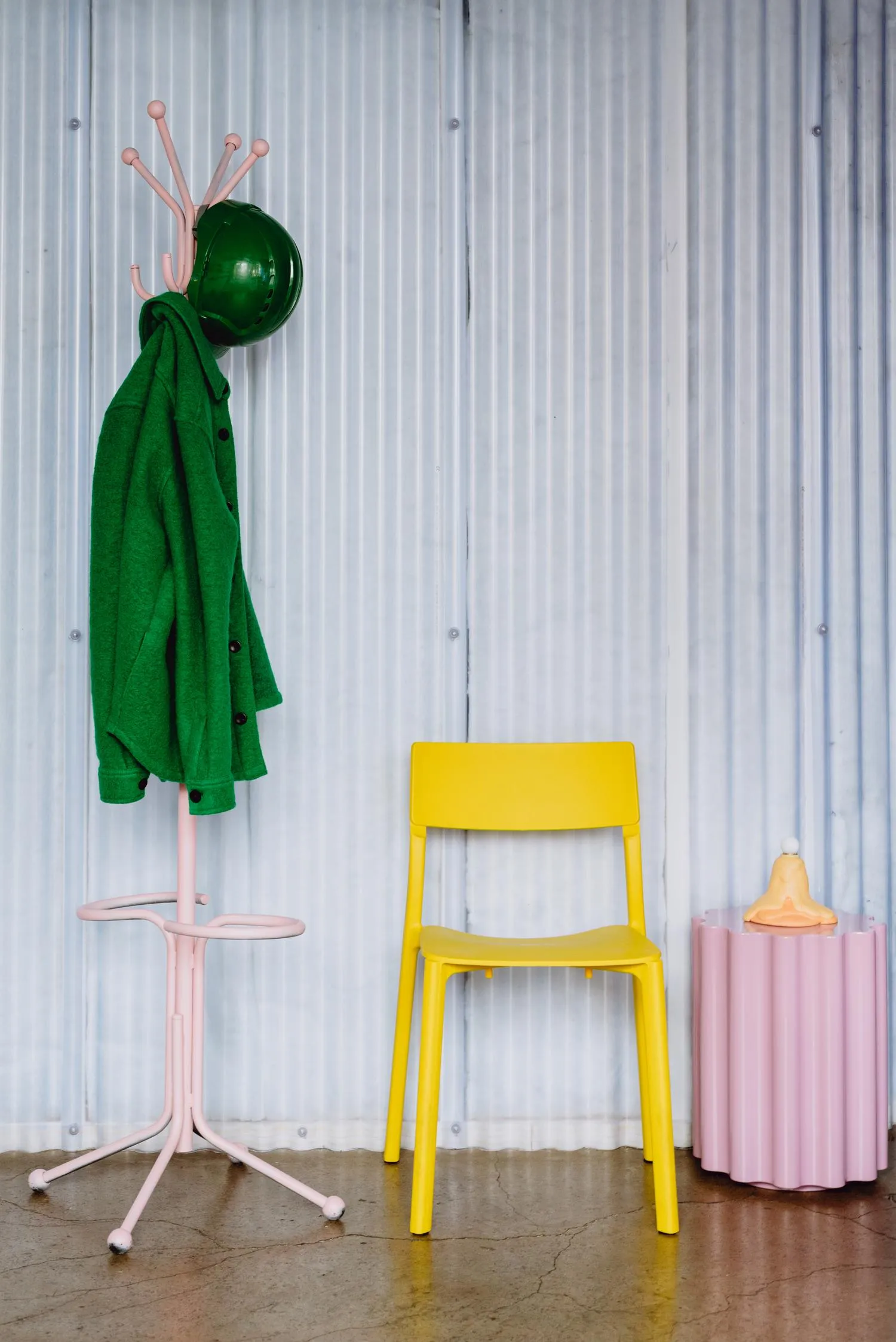 Zoomed in photo showing a coat rack, yellow chair and a small coffee stand, with a metal wall behind. By Office S&M, RIBA Chartered Architectural Practice in London.