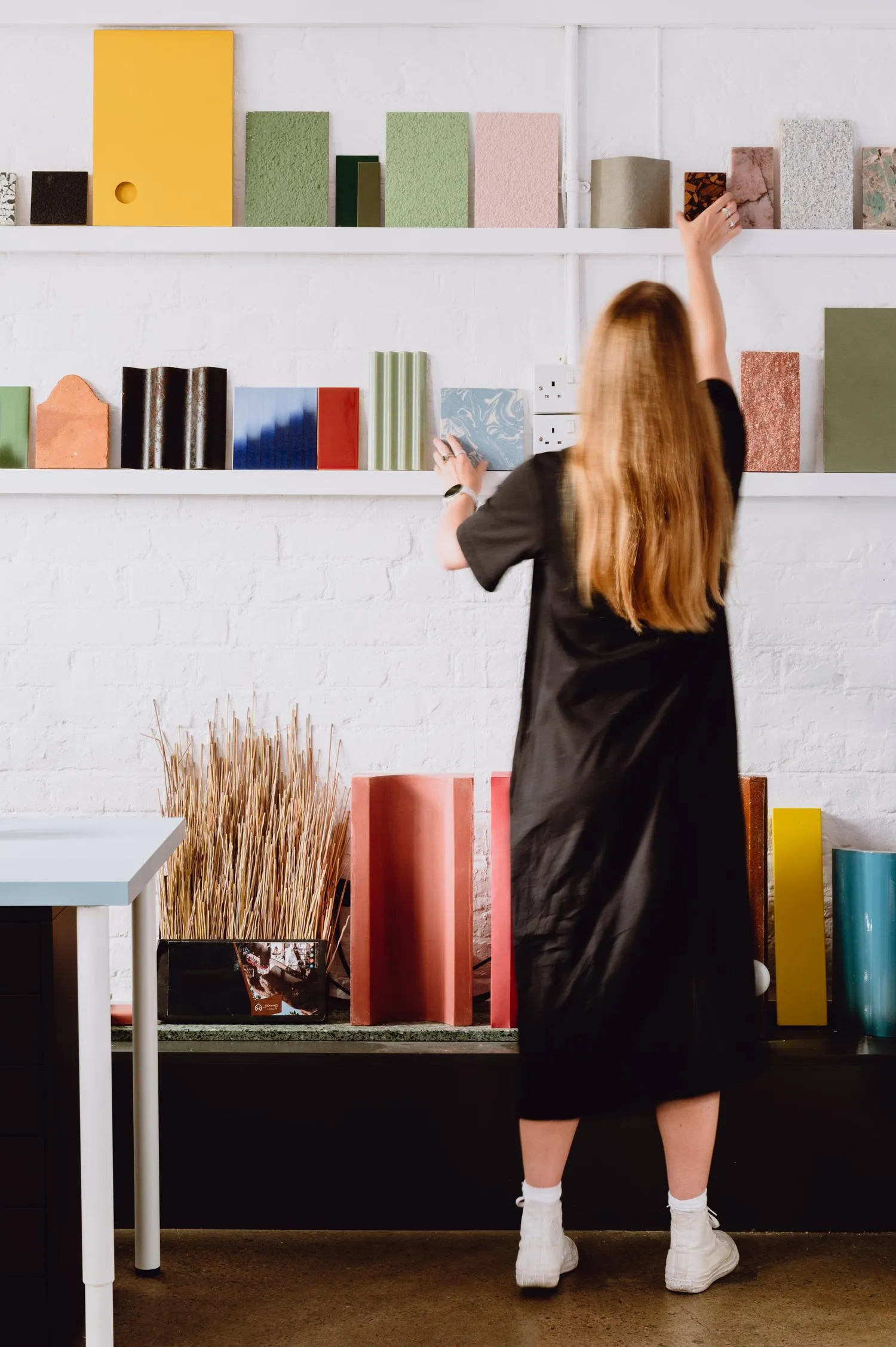 Photo of a person reaching out sample materials on long shelving units. By Office S&M, RIBA Chartered Architectural Practice in London.