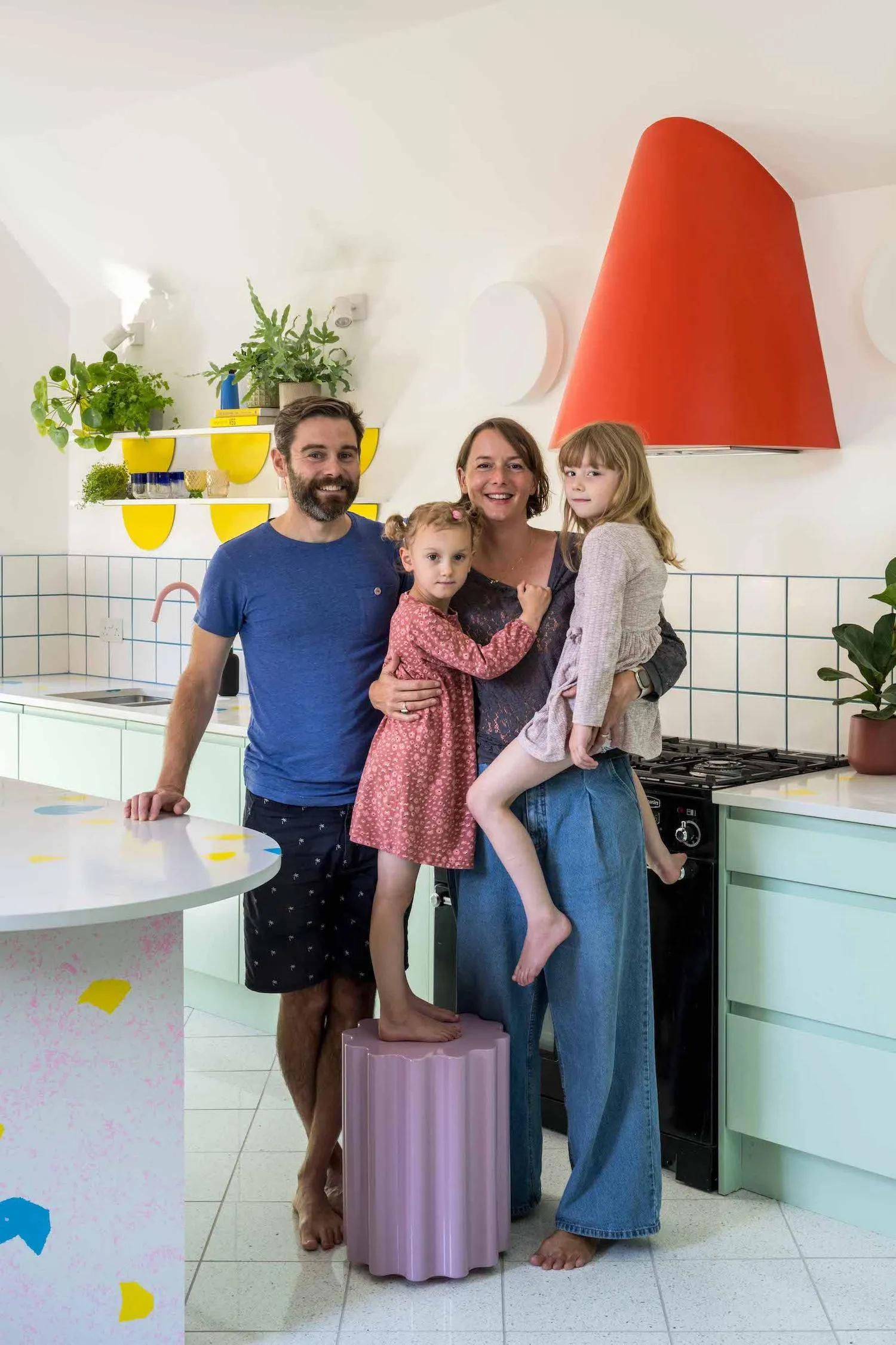 Photo of the owners of the house and their daughter, all stood in the kitchen. By Office S&M, RIBA Chartered Architectural Practice in London.