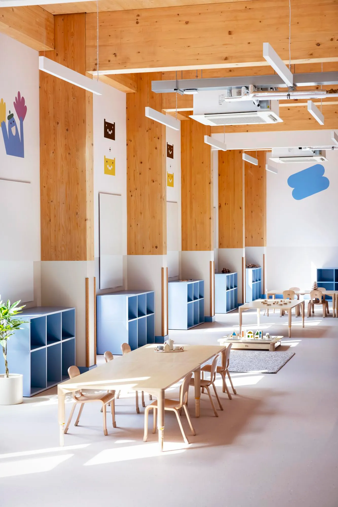 Photo of the internal nursery space, showing the blue shelving units and timber structure. By Office S&M, RIBA Chartered Architectural Practice in London.