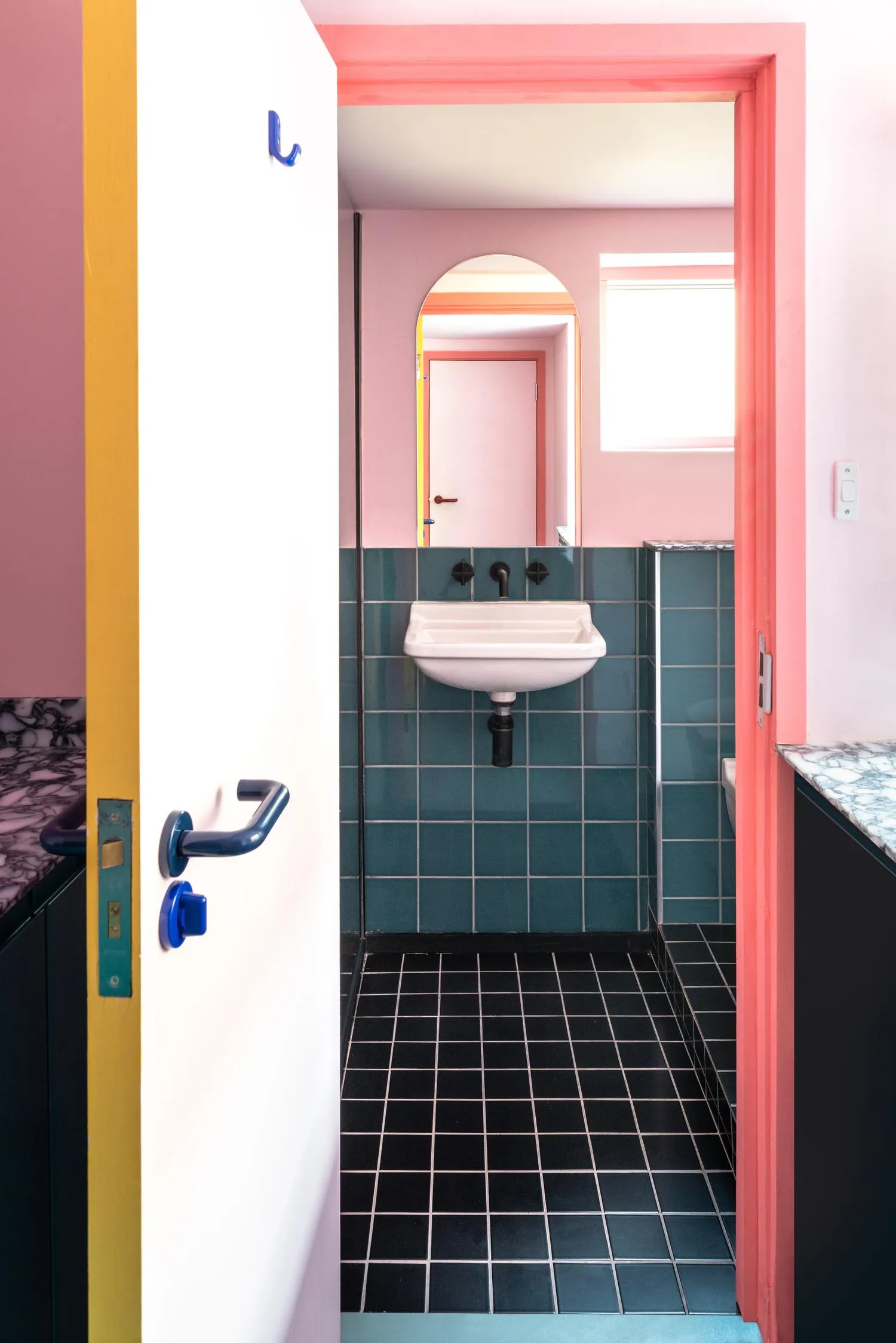 Photo of the bathroom seen through the pink doorway. By Office S&M, RIBA Chartered Architectural Practice in London.