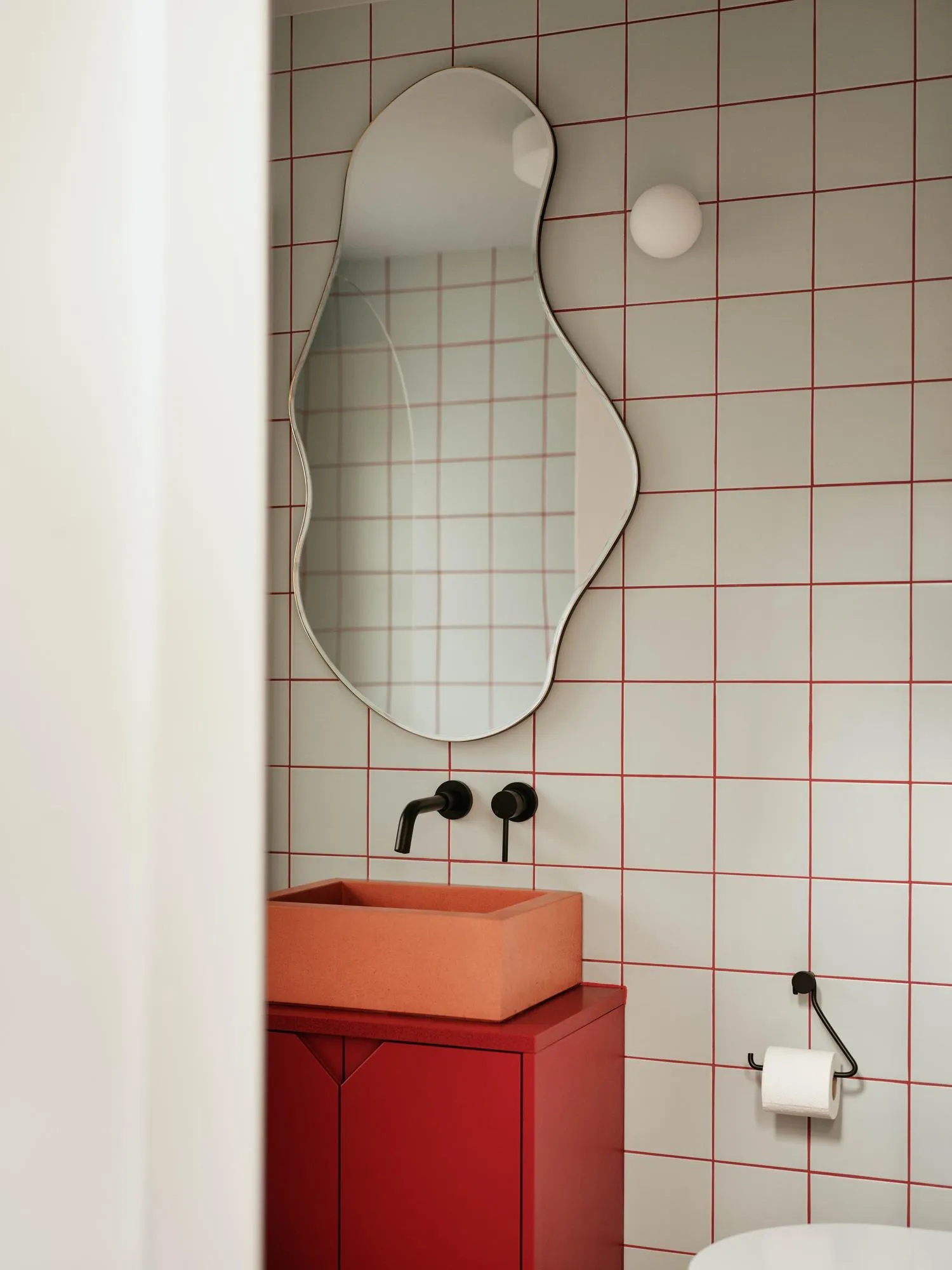 Photo of a small bathroom, showing an orange sink and playful mirror on the wall. By Office S&M, RIBA Chartered Architectural Practice in London.