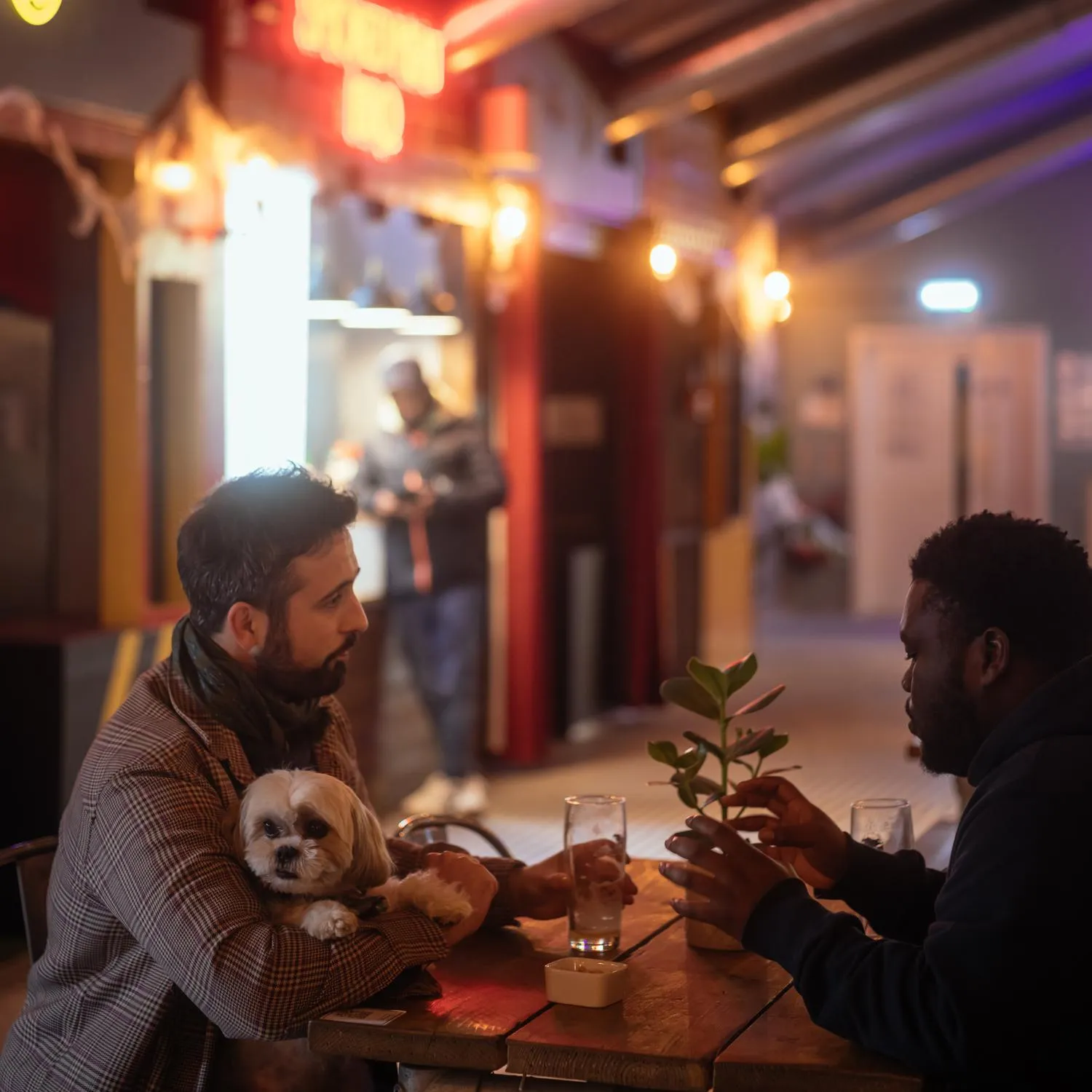 Photo of two men chatting at a small table. By Office S&M, RIBA Chartered Architectural Practice in London.