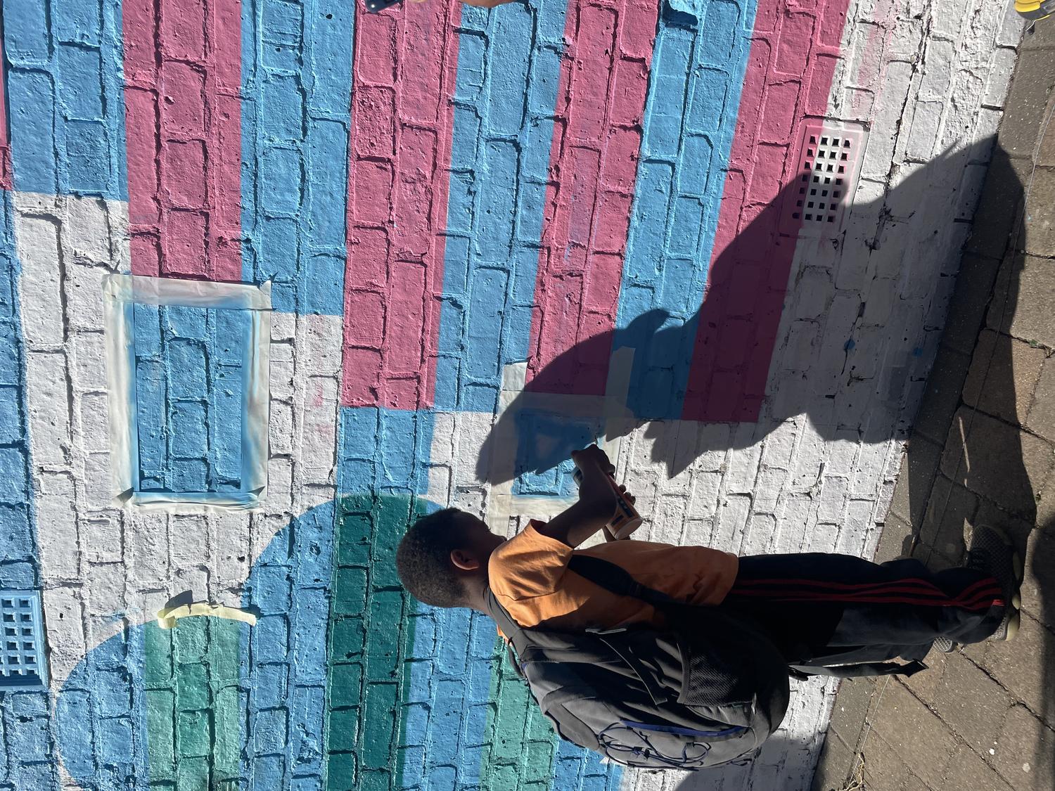 A young person helping with painting a mural on the wall. By Office S&M, RIBA Chartered Architectural Practice in London.