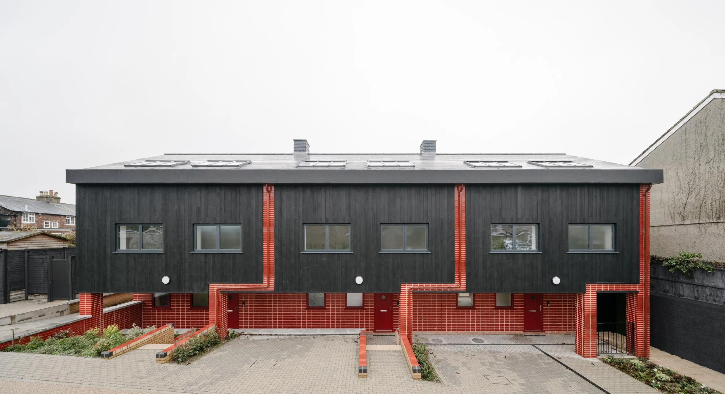 Photo showing southern facade of the building, with characteristic red accent. By Office S&M, RIBA Chartered Architectural Practice in London.