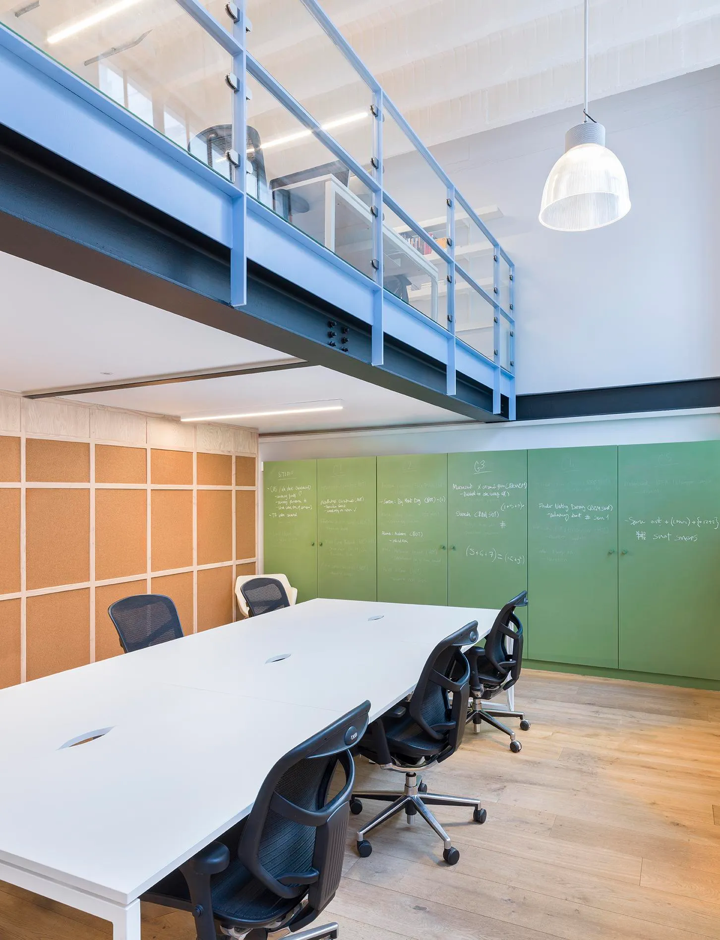 Photo showing a set of desk spaces, with an upper mezzanine level above. By Office S&M, RIBA Chartered Architectural Practice in London.