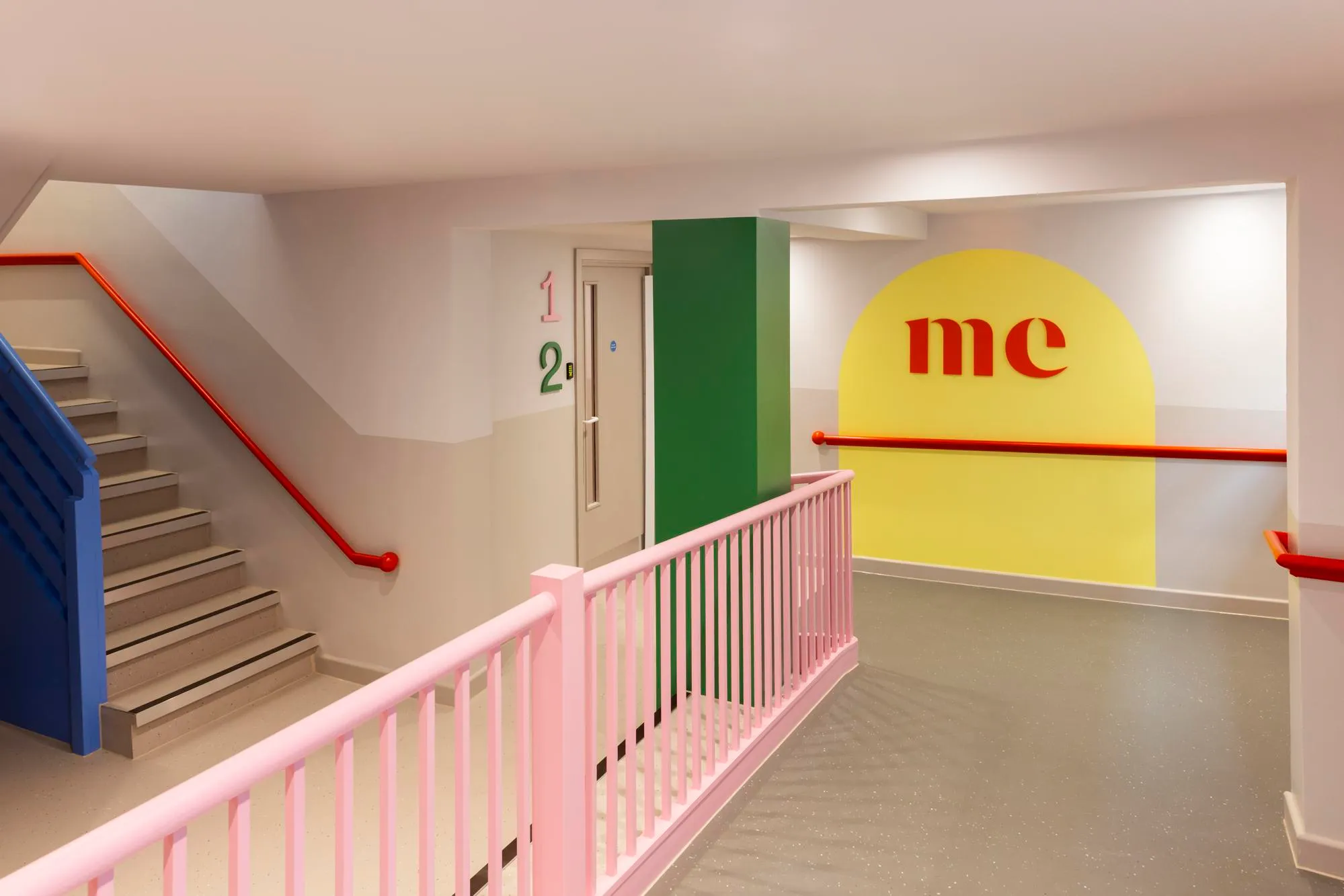 Circulation space, showing pink railings, red railings on the wall and yellow accent wall in the background. By Office S&M, RIBA Chartered Architectural Practice in London.