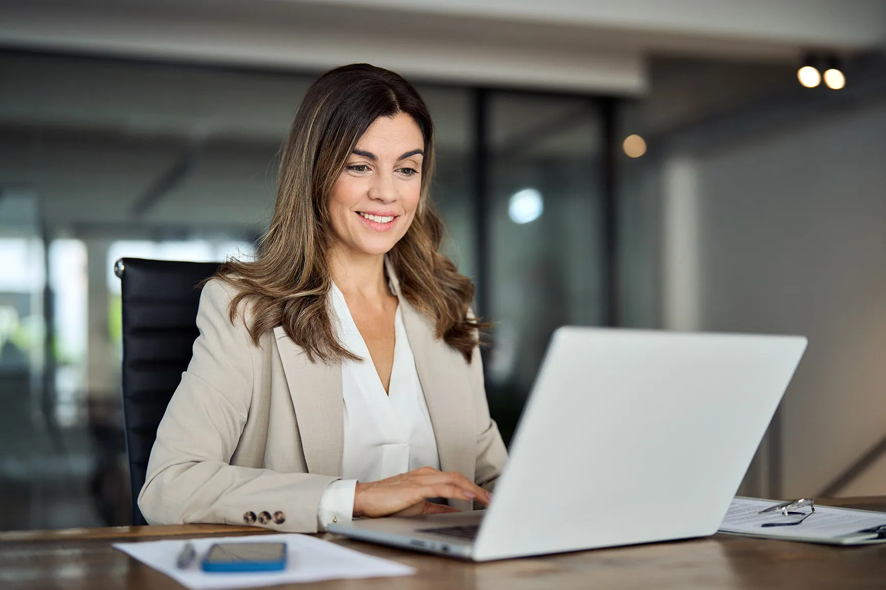 Woman in suit looking at her laptop in the office