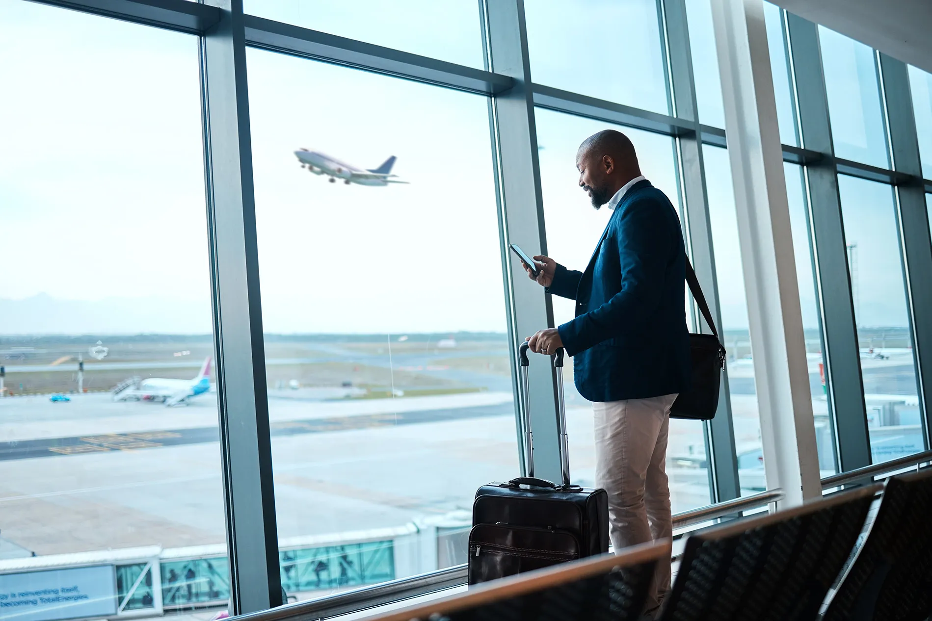 Business-man at an airport looking at his phone