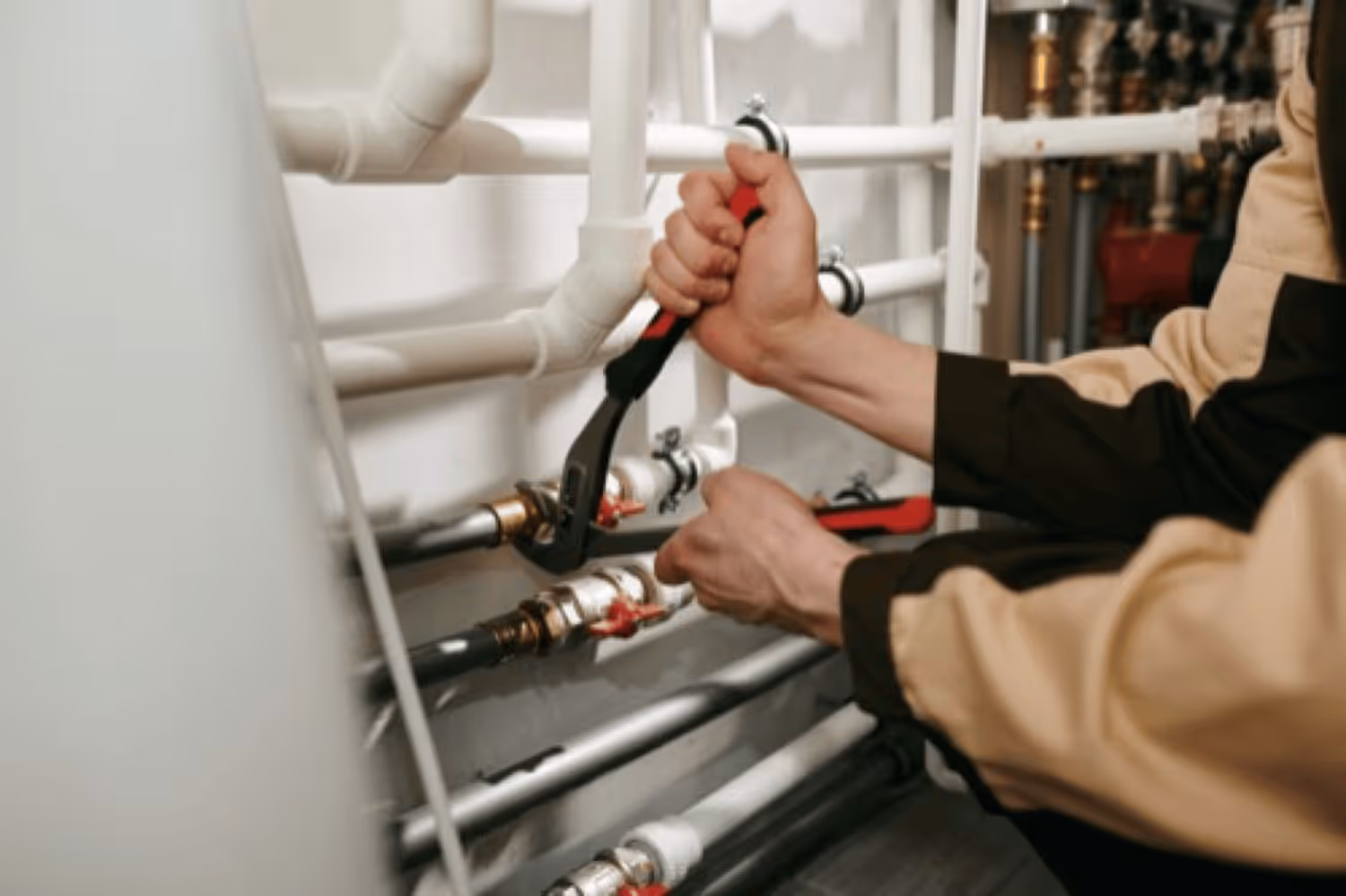 Person wearing protective gloves uses a metal trowel to smooth plaster or putty onto a white interior wall.
