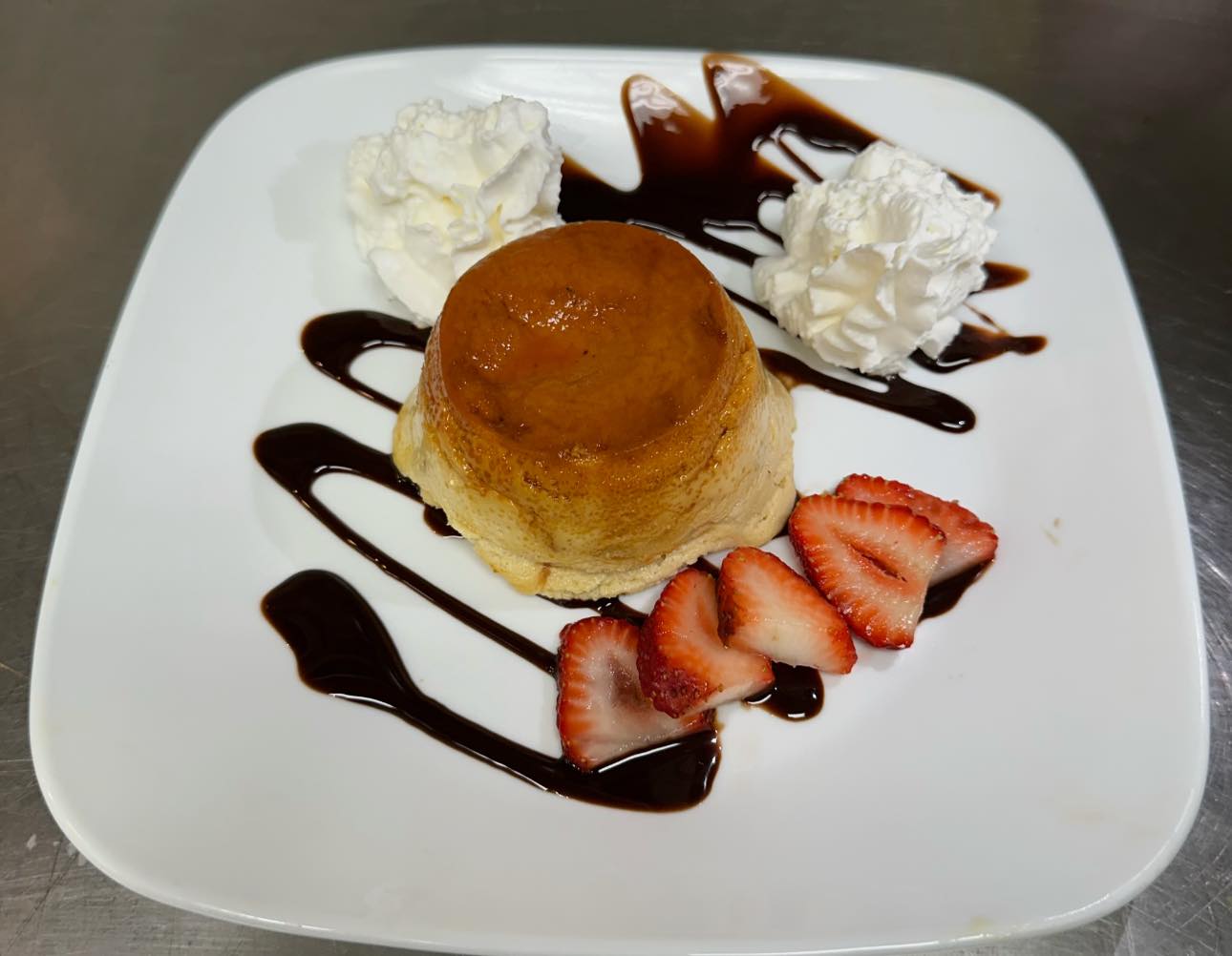 A plate of food with a strawberry and whipped cream on top.