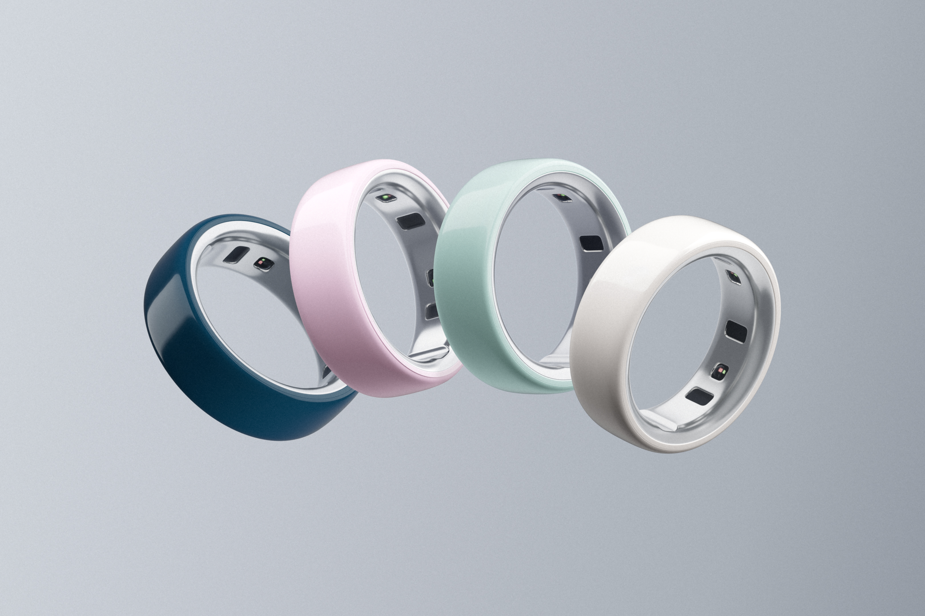 four Oura rings in different pastel colors on grey background