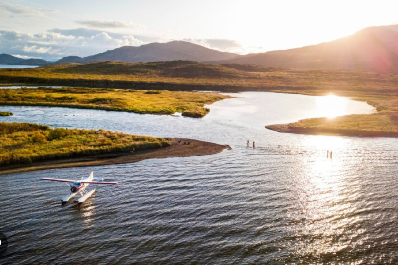 Scenic fishing lodge waterfront at sunset with boats on calm water, representing world-class fishing experiences rooted in place.