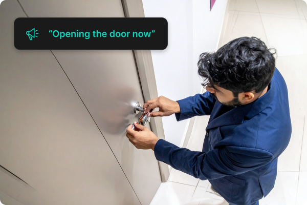 A man trying to open the door, and a someone is telling him that they will open the door through the app.