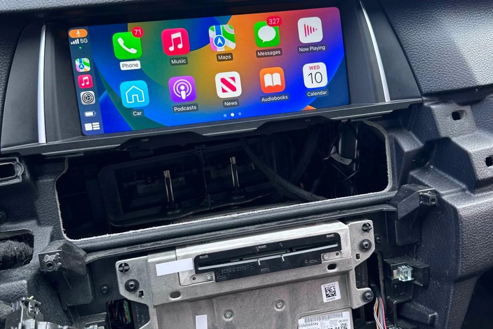 Mains d'une personne travaillant sur un panneau intérieur de voiture beige avec un outil électrique noir.