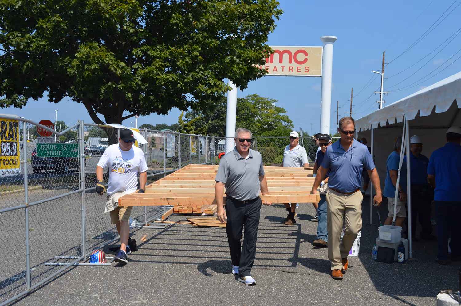 Construction site with a two-story house under framing and a trailer marked BEW Local 400 parked on the street.