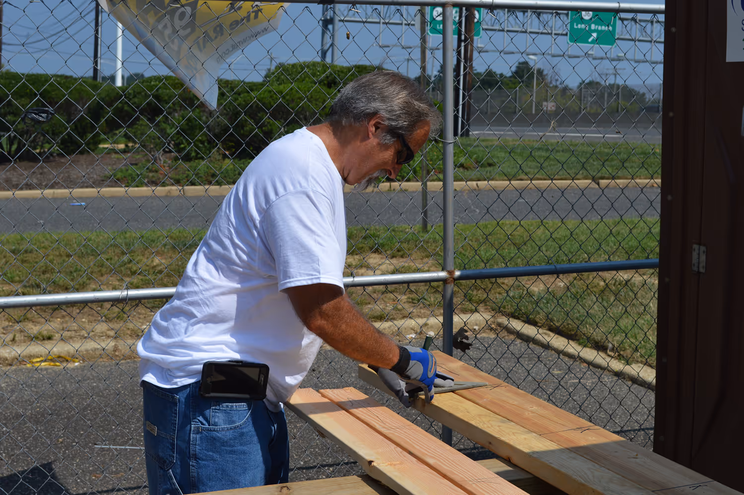Group of people unloading boxed food from a truck with IBEW Local 400 branding into a red metal cart outdoors on a sunny day.