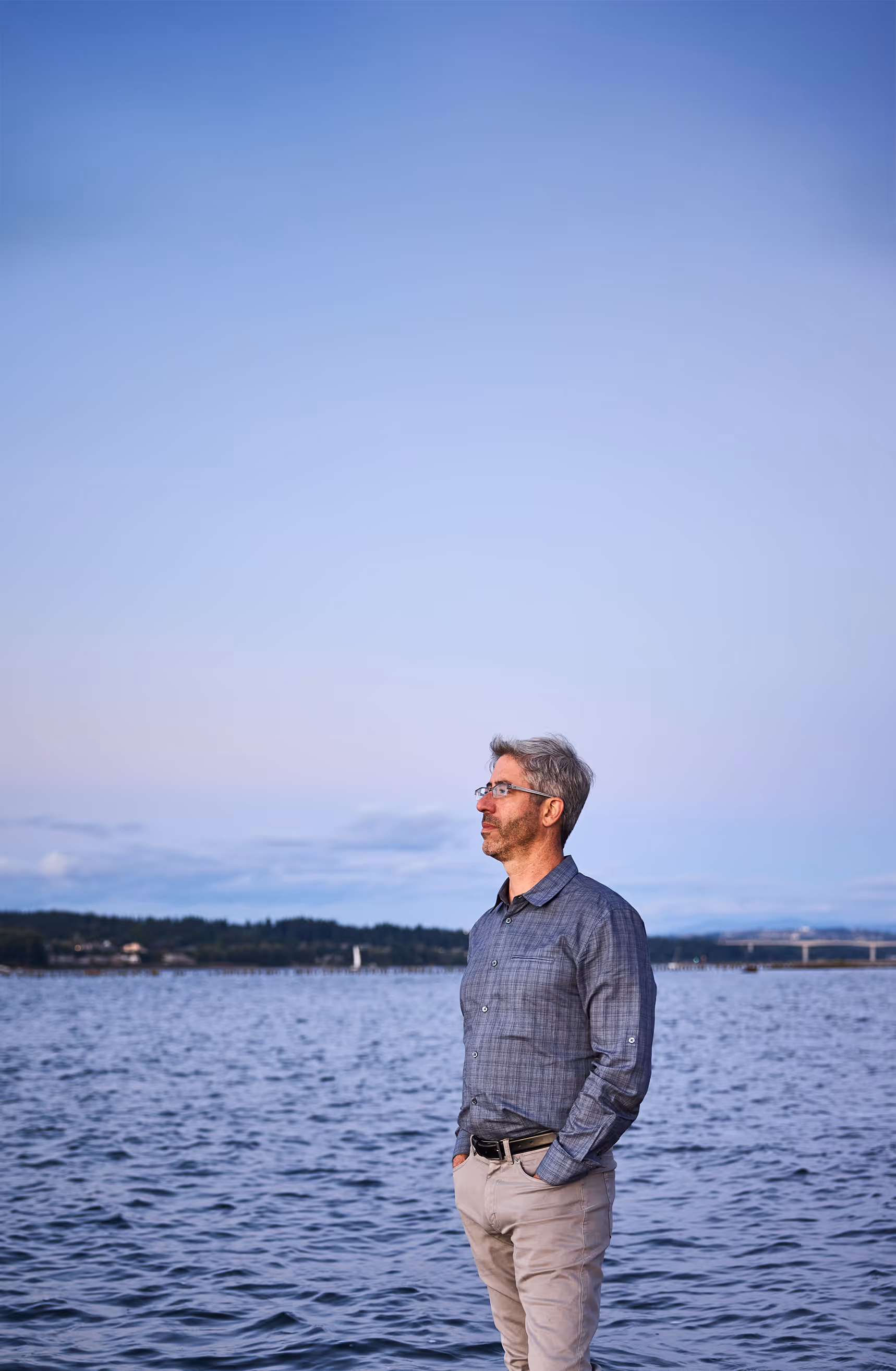 Jordan Plawner standing at the beach, looking pensively out at Portland.