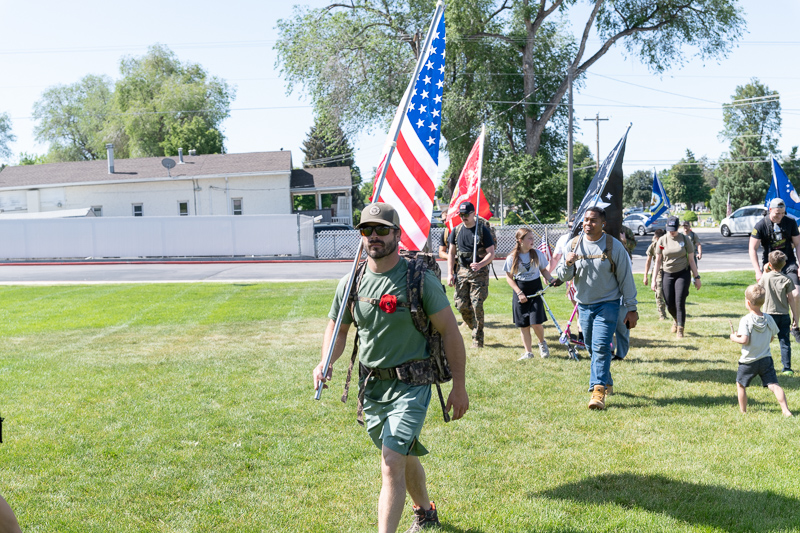 Utah veterans and supporters march with American and military flags on grass