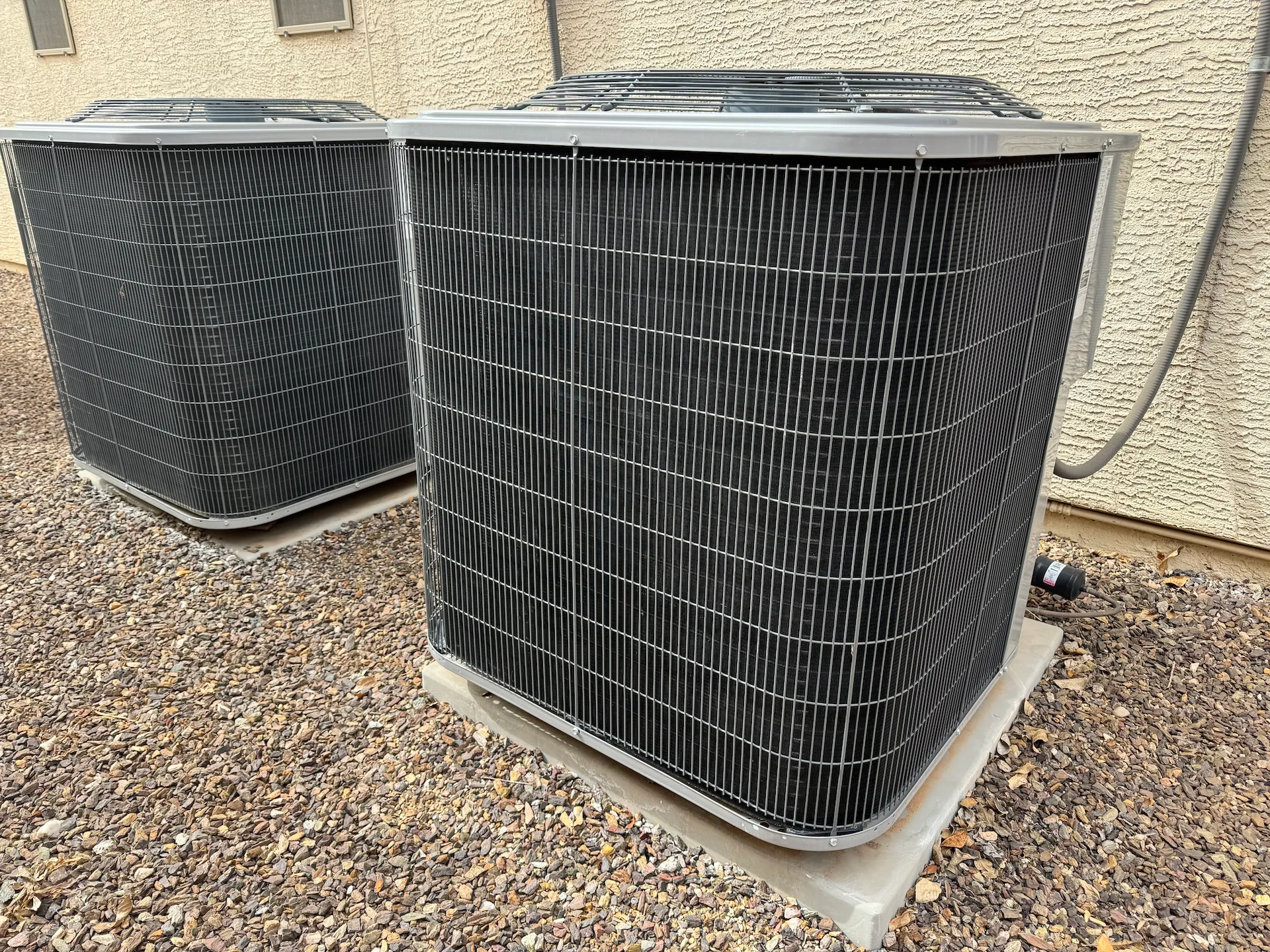 front of two ac condenser units on side of house