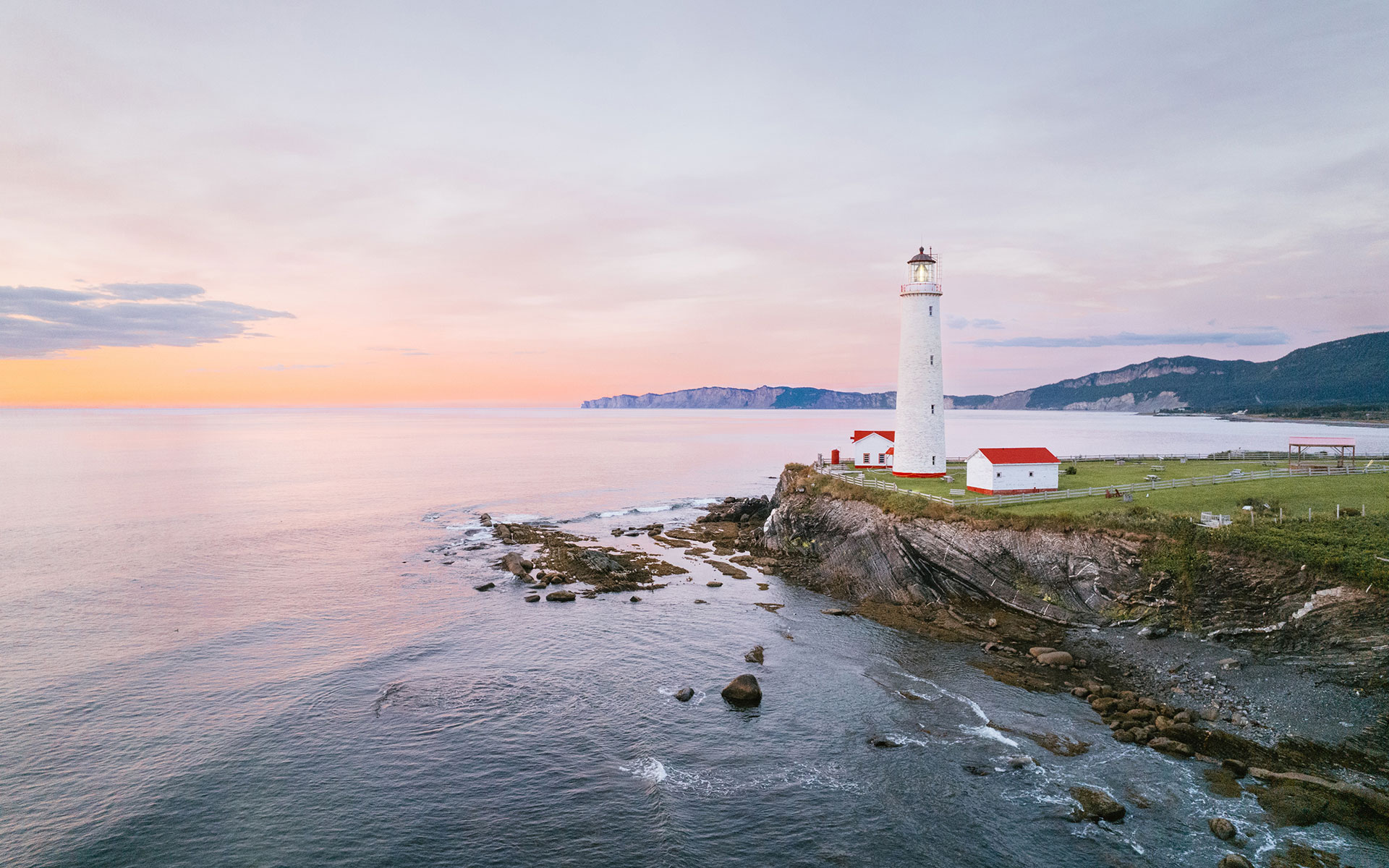 A light house sitting on top of a cliff next to the ocean.