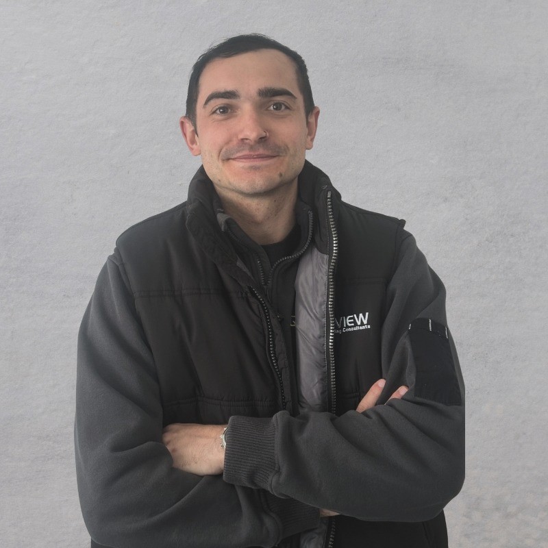 Photo of Tyler Peters building consultant standing infront of a wall with Overview jacket on