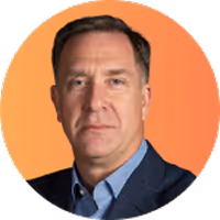 Headshot of a middle-aged man with short brown hair wearing a dark blazer and light blue shirt against an orange gradient background.