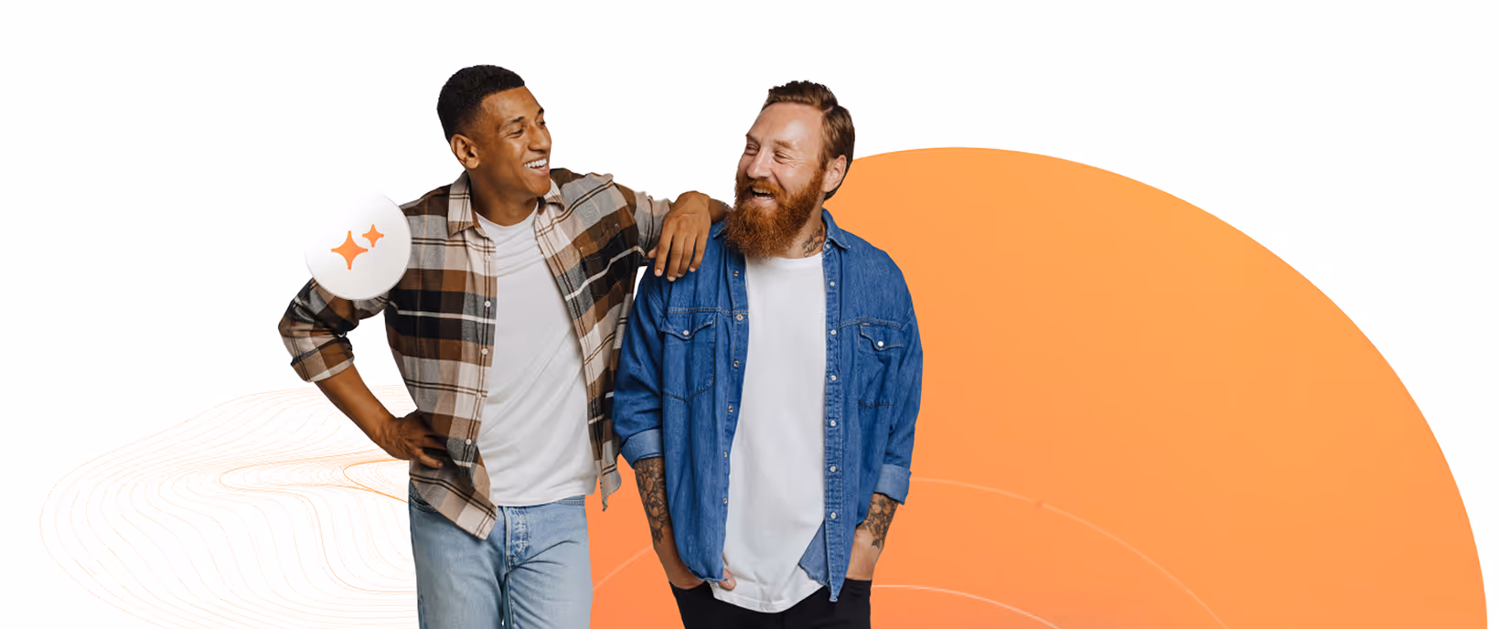 Two men laughing and standing together, one in a plaid shirt and jeans, the other in a blue denim jacket and white t-shirt with tattoos on his arms.