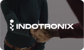 Two people shaking hands behind the white INDOTRONIX logo on a dark background.