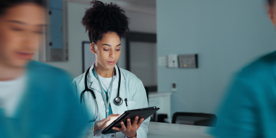 Healthcare worker with a stethoscope reviewing a tablet in a hospital