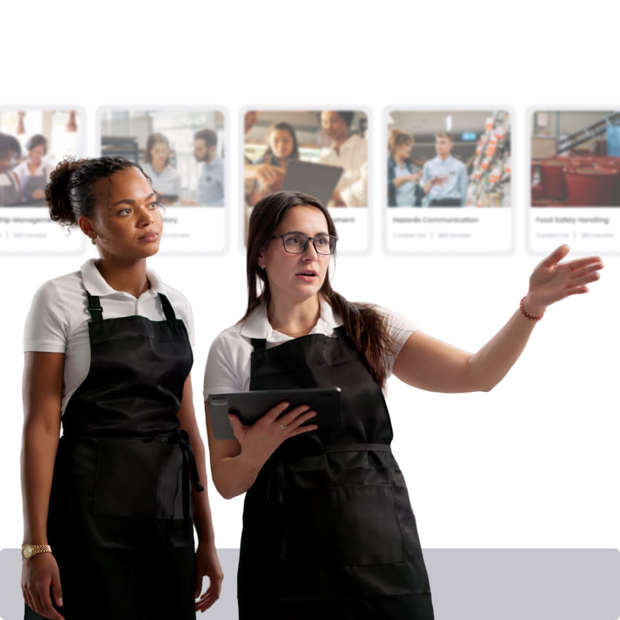 Two hospitality workers in aprons reviewing a tablet in front of course cards