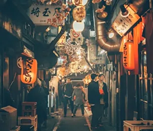 People walking through a narrow alley filled with lanterns in Japan.