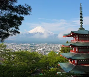 Red pagoda overlooking Mount Fuji and a city.