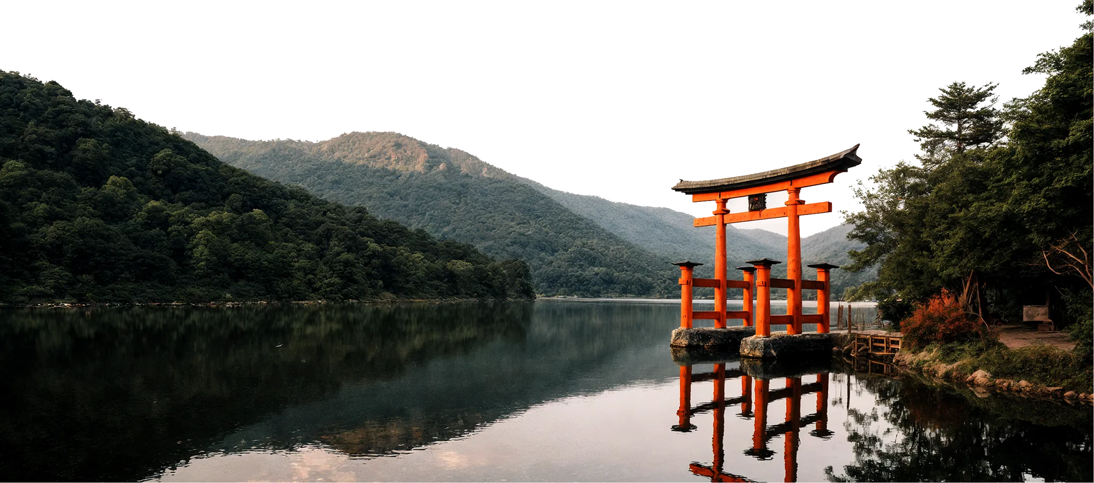 Traditional red torii gate in a lake surrounded by mountains.