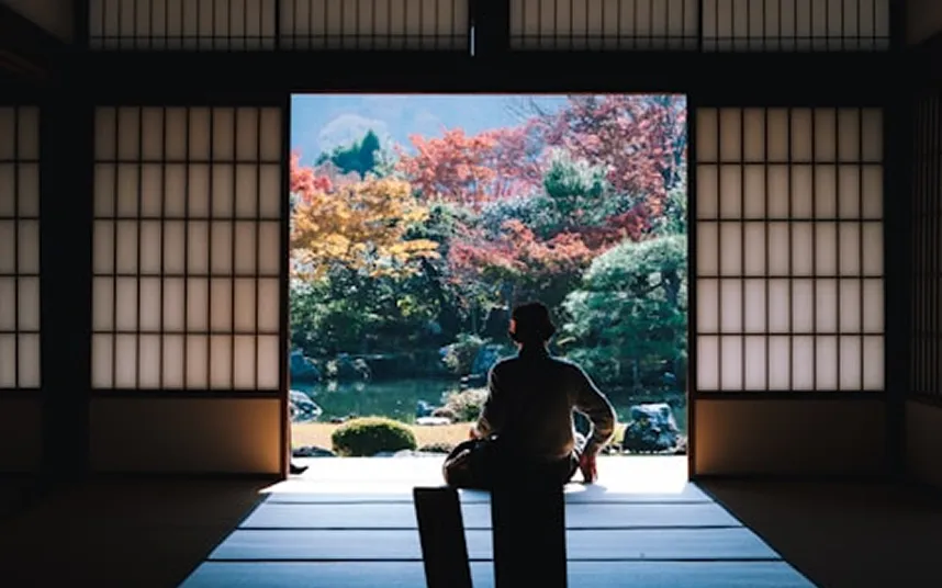 Person sitting in a Japanese room with a garden view.