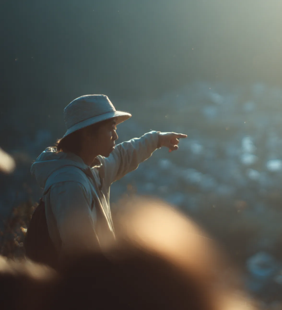 Person pointing toward the horizon in soft sunlight