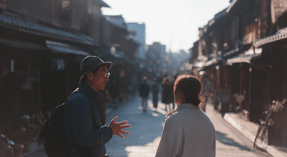 Two people talking on a traditional street in warm light