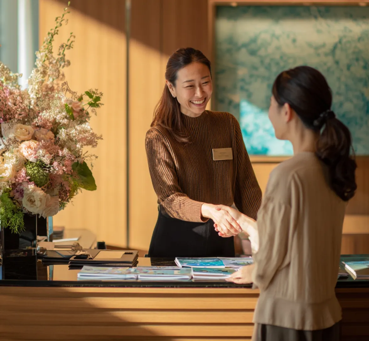 Receptionist shaking hands with a visitor.