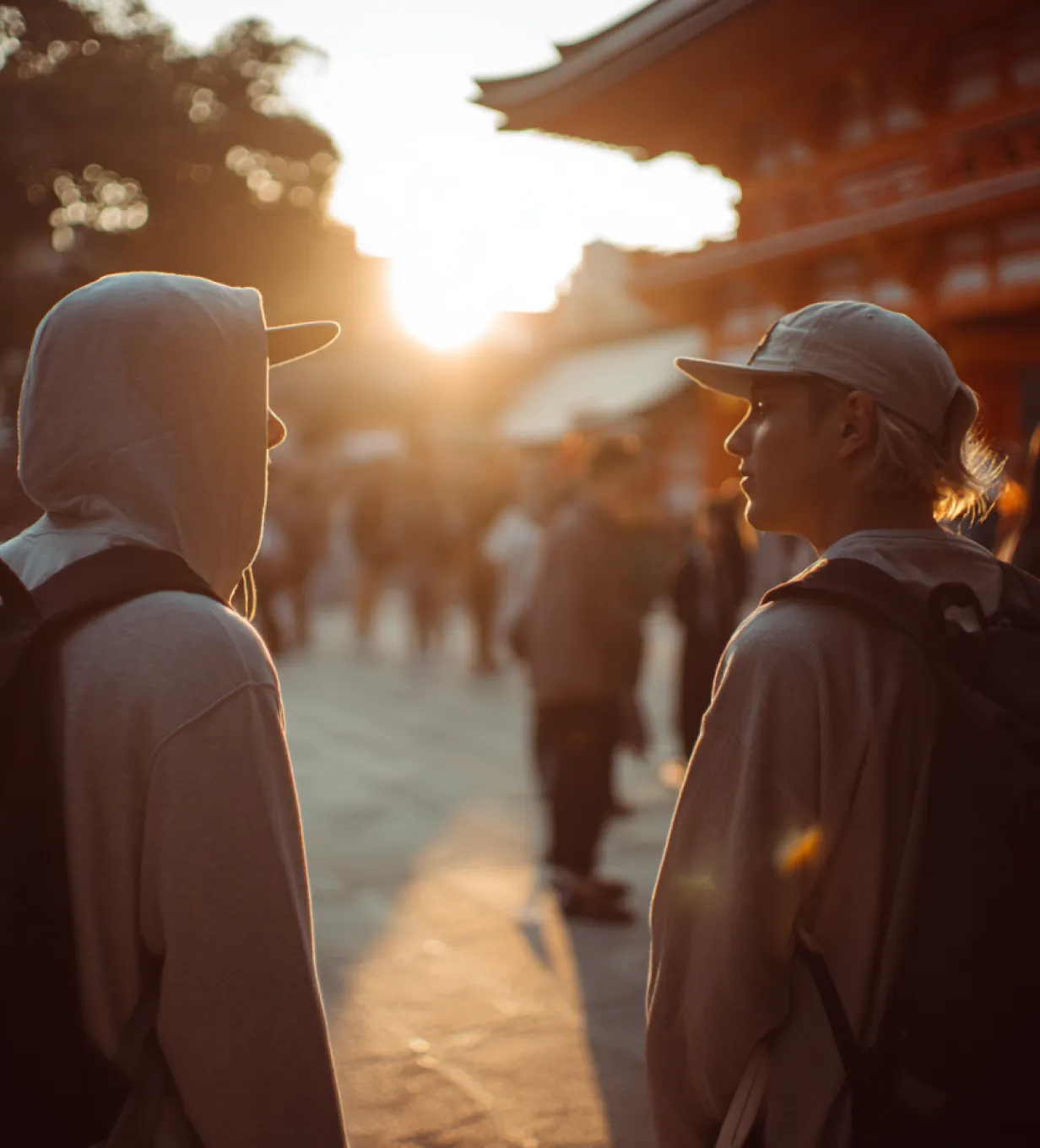 Two people talking in a sunlit outdoor area near a shrine.