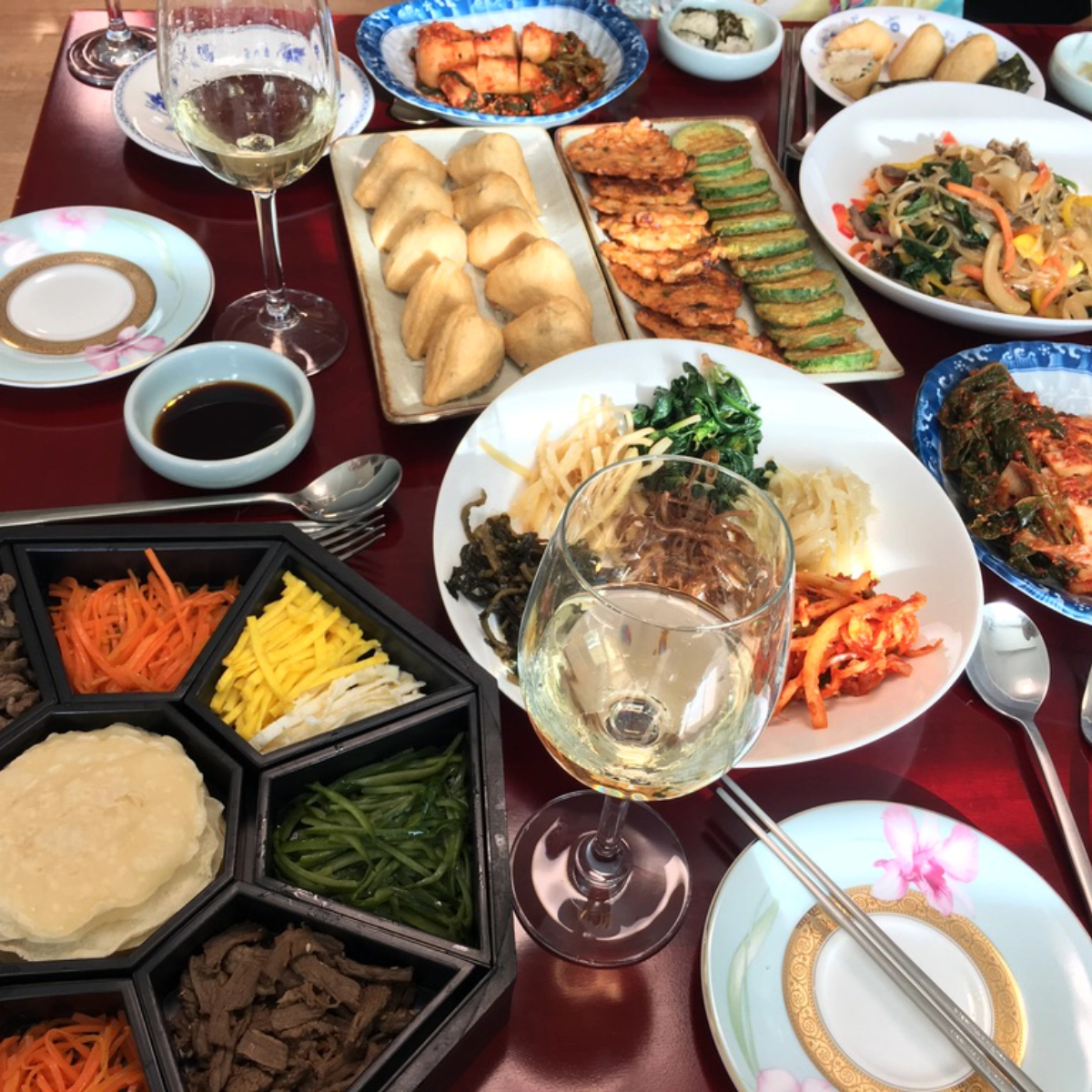 Korean hansang charim table with rice paper wraps, assorted banchan, jeon, dumplings, kimchi, and shared dishes arranged across the table.