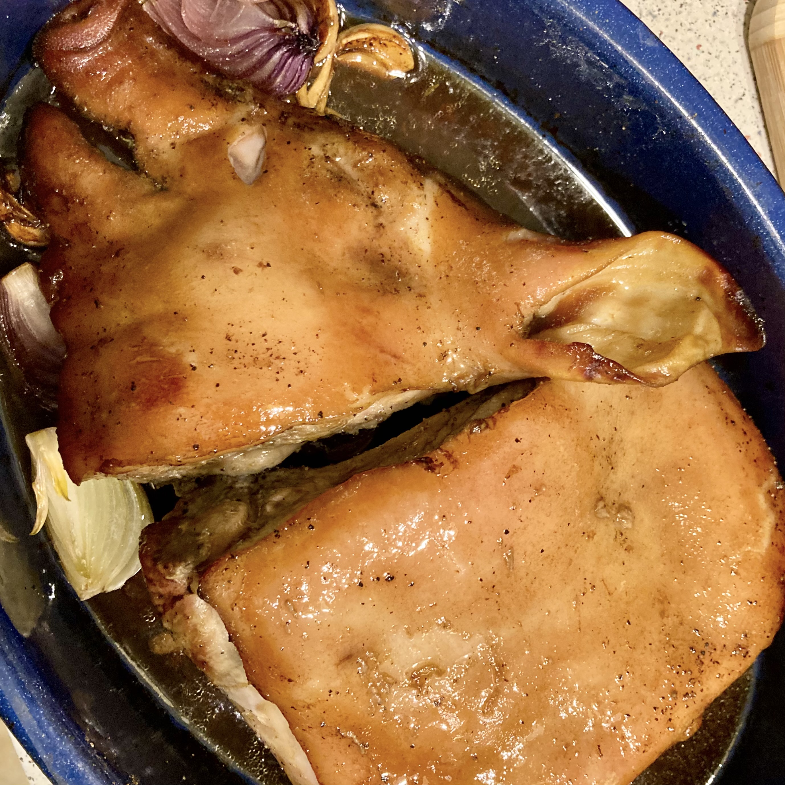 Roasted pig’s head in a baking dish with garlic and onions, prepared for a Christmas meal.