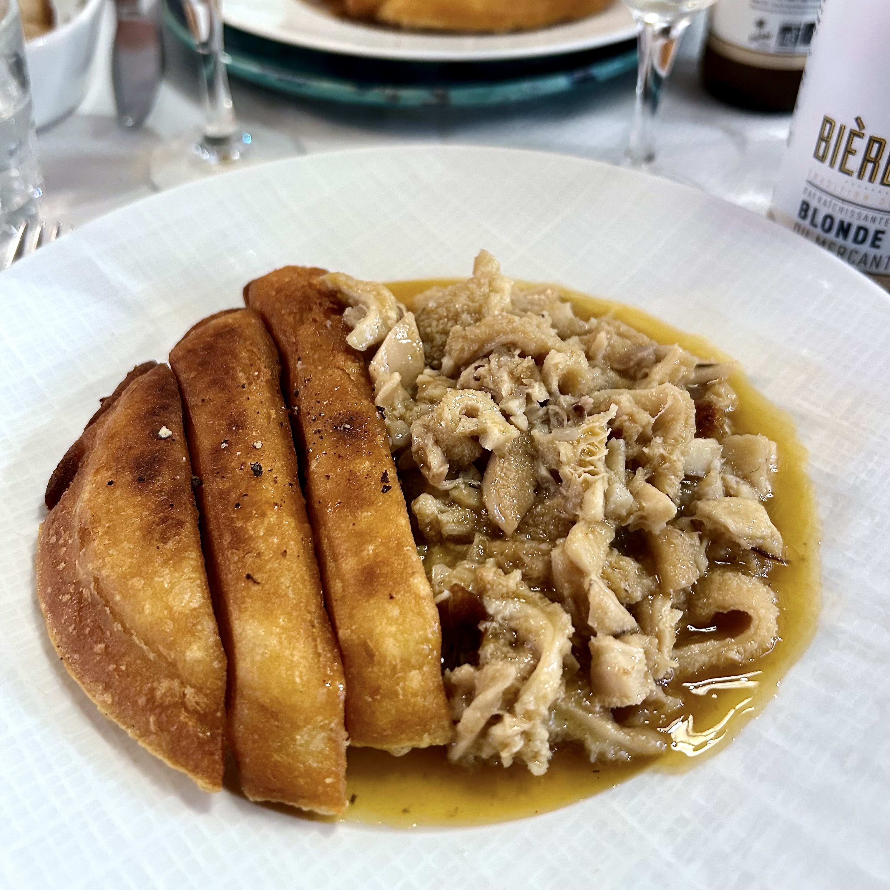 Veal tripe in sauce served with slices of socca, a chickpea based fried dish, on a plate in Nice, France.