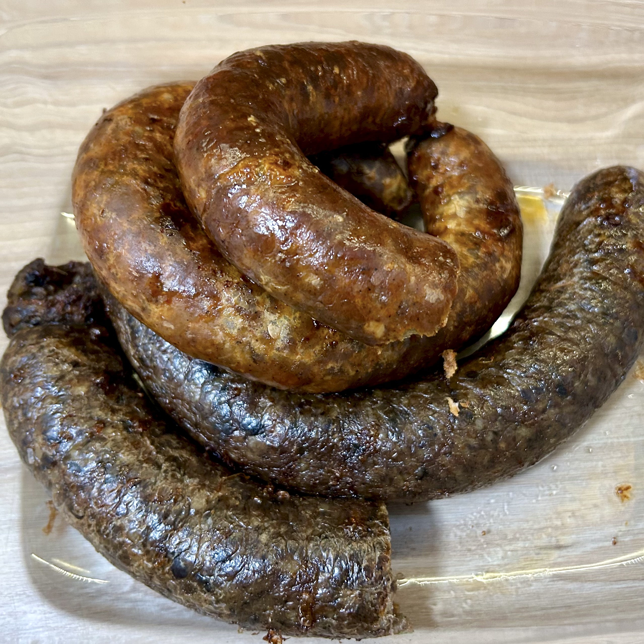 Hungarian liver and blood sausages (hurka) stacked in a glass baking dish.
