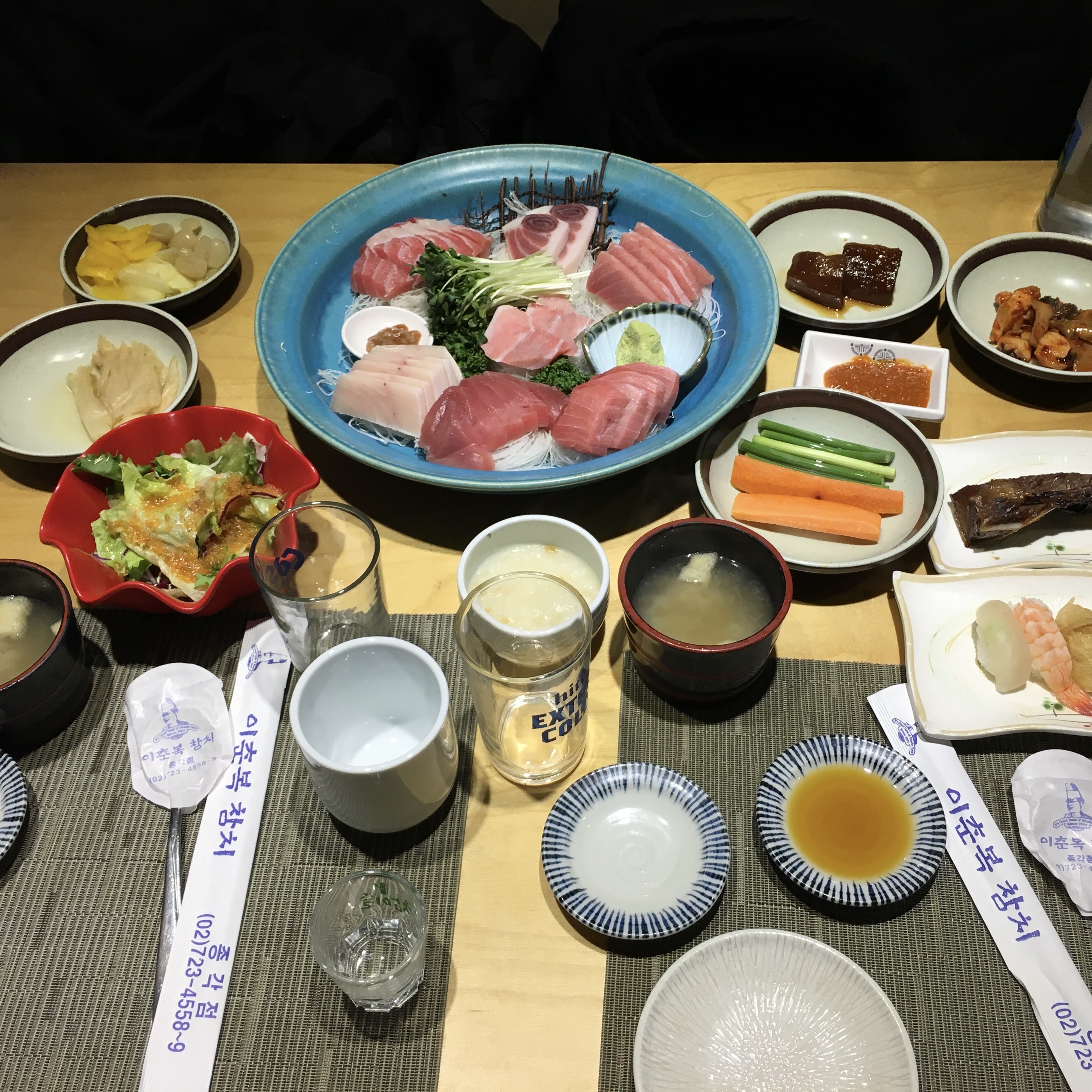 Korean sashimi meal with tuna and an assortment of small side dishes served together on a table.