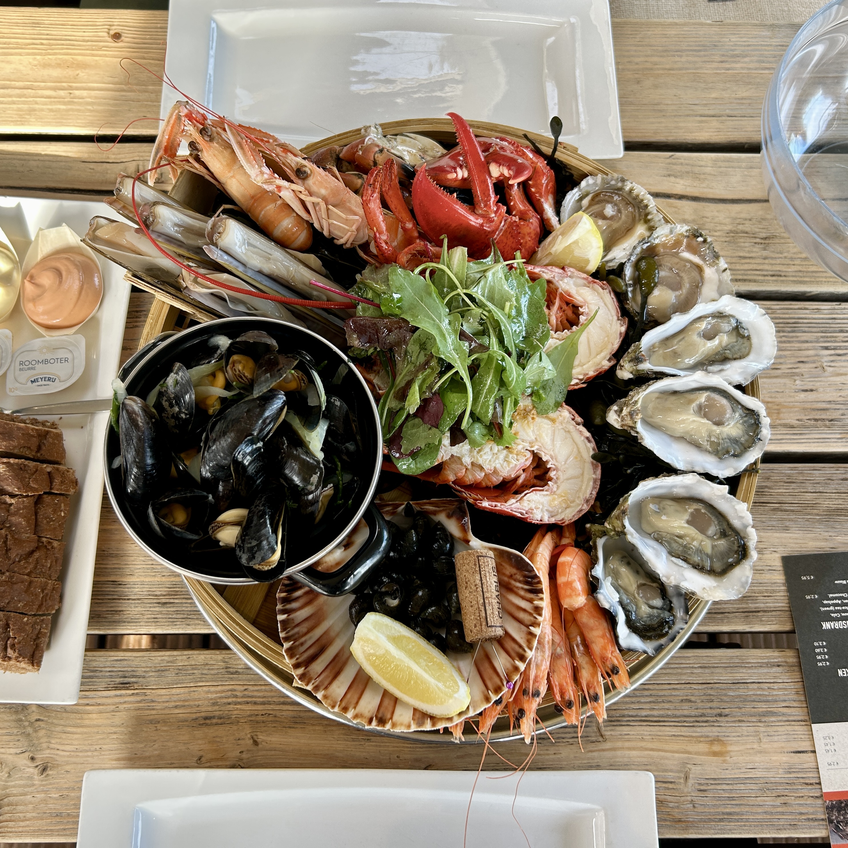 Seafood platter with oysters, mussels, shrimp, lobster, and small sea snails, with metal pins placed in a wine cork.