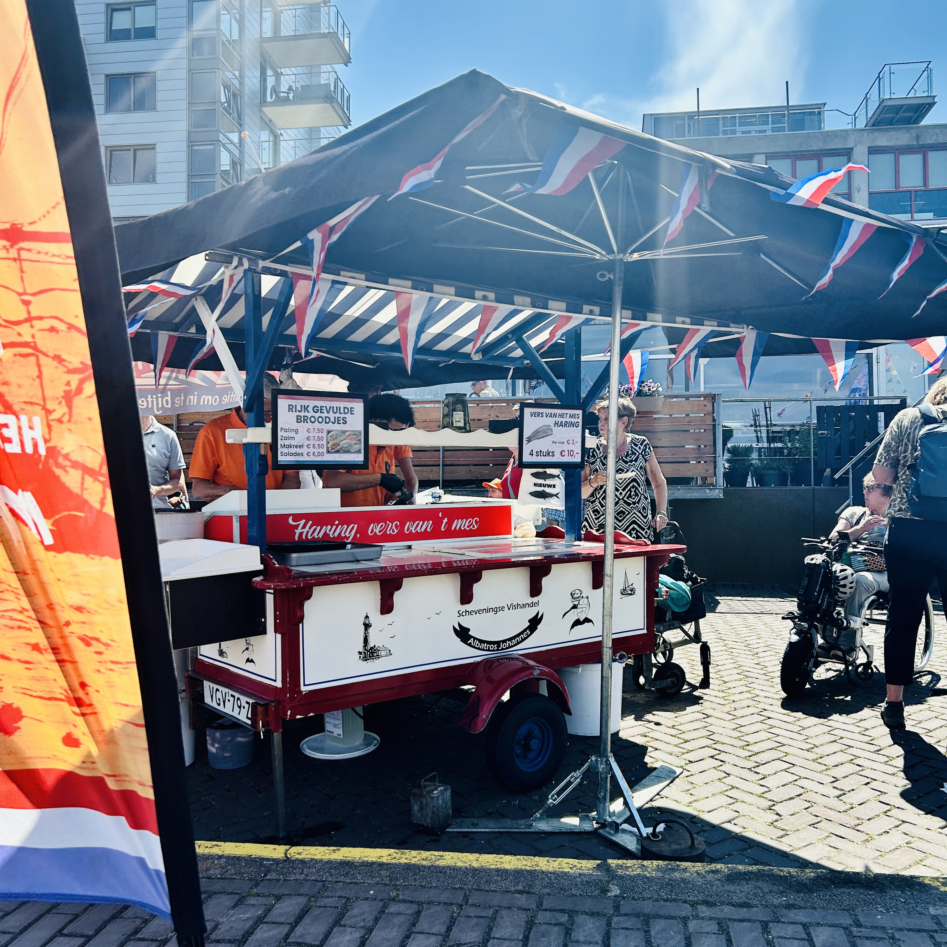 A Dutch herring stall at Vlaggetjesdag decorated with red, white, and blue bunting.