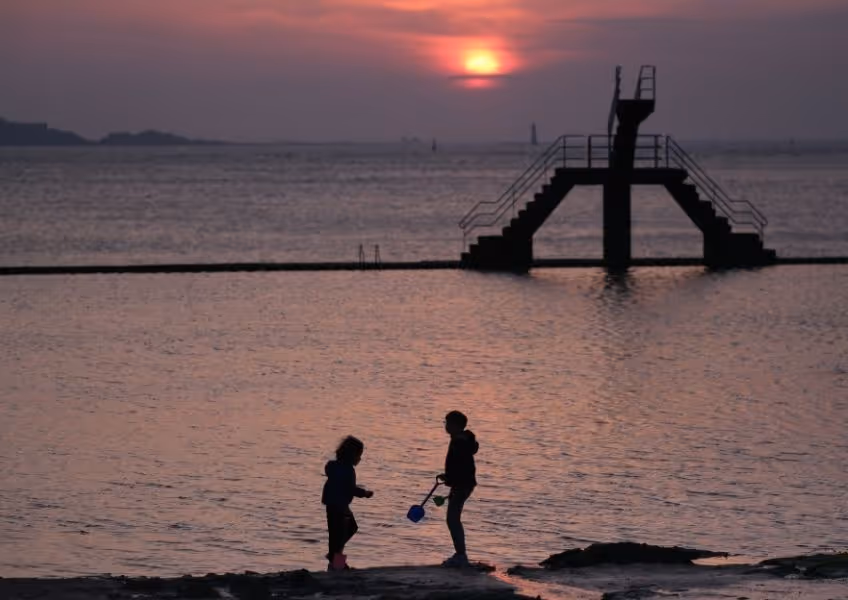 Vacances en famille au coucher de soleil sur la plage du Sillon à Saint-Malo, proche du Grand Hôtel de Courtoisville, hôtel 4 étoiles de luxe.